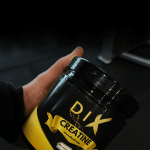 Pot de créatine DIX en main sur fond sombre, idéal pour la nutrition sportive et les compléments alimentaires.