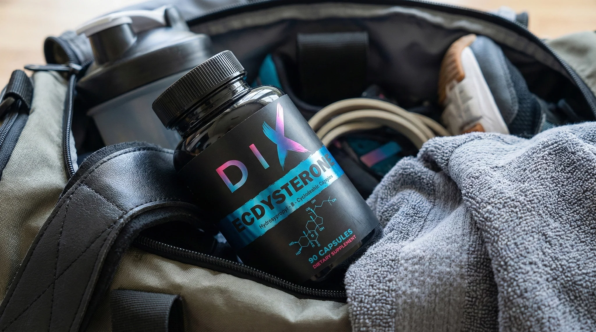 Bouteille de complément alimentaire DIX CD STEROID dans un sac de sport, entourée d'accessoires de gym.