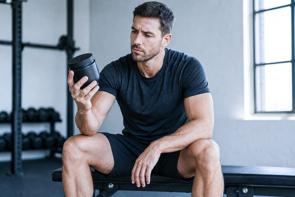 Sportif naturel sceptique tenant un pot de complément anabolisant