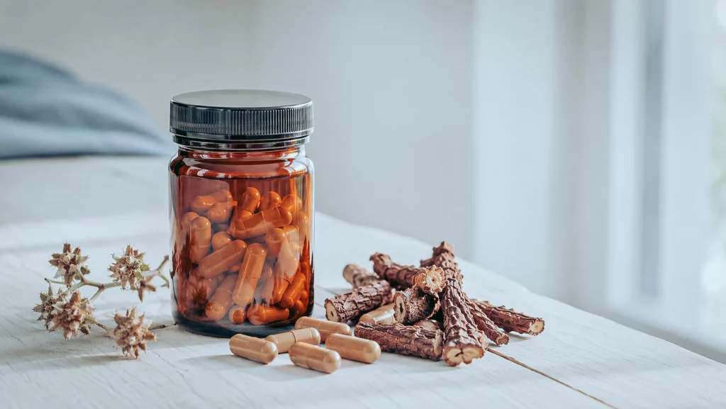Frasco de Tribulus ao lado de raízes de rodiola cortadas e cápsulas
