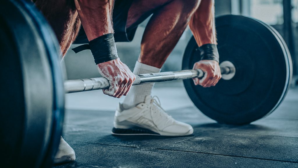 Mains sur une barre chargée à la salle de musculation, effort intense