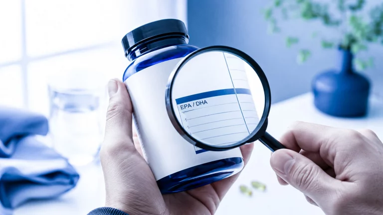 Bouteille de compléments alimentaires Omega-3 examinée avec une loupe, étiquette bien visible.