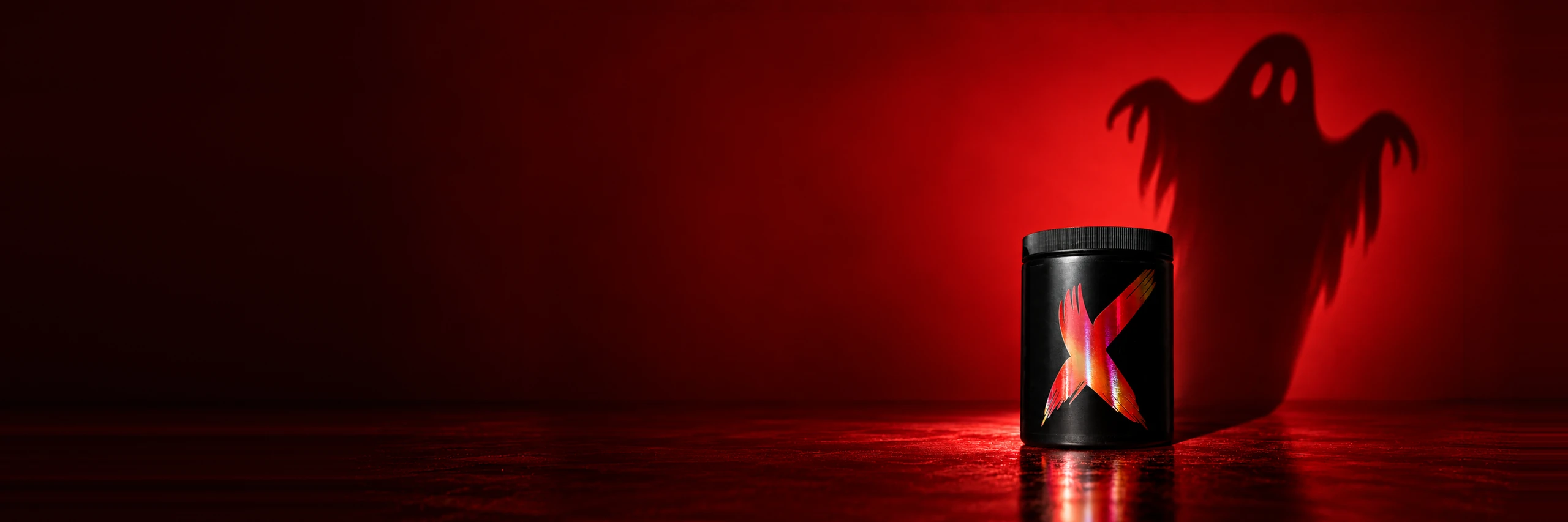 Pot de Pre-Workout DIX au X rouge dont l'ombre dessine un fantôme sur un mur rouge